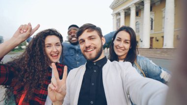 Şehir merkezinde fotoğraf makinesiyle selfie çeken ve el hareketleriyle pozlar veren çok ırklı turistlerin görüntüsü olumlu duygular ifade ediyor..