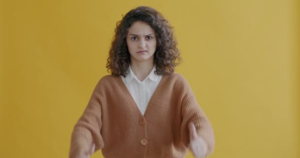 不快乐的年轻女子的画像 低垂着大拇指 看着镜头 在黄色的背景下表达失望 — 图库视频影像
