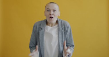 Heyecanlı bir bayanın yavaş çekimde çığlık atması ve kollarını kaldırması sarı arka planda iyi haberlerin keyfini çıkarması. Olumlu ve neşeli insanlar konsepti.