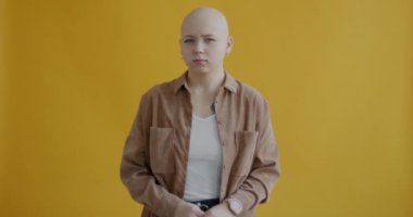 Ciddi bir genç kadının portresi parmağını sallıyor ve sarı arka plandaki kameraya bakıyor. Vücut dili ve insan kavramı.