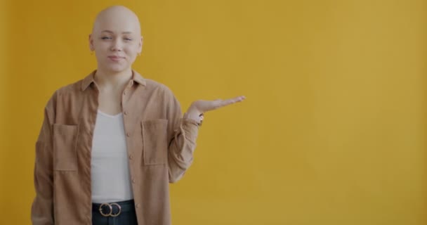 明るい女性の肖像空の場所に横に指摘し 黄色の色の背景に立って笑顔 人と広告のコンセプト — ストック動画