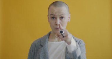 Kendine güvenen bir kadının kamerayı göstermesi ve sarı arka planda telefon araması istemesi. İnsanlar ve iletişim konsepti.