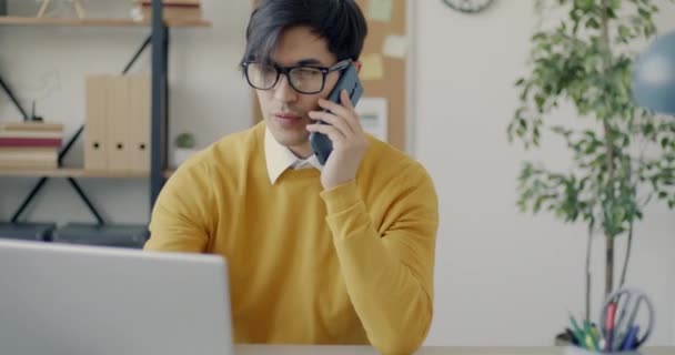 有野心的亚洲商人在办公室里用笔记本电脑和手机讲话 通信和业务发展概念 — 图库视频影像