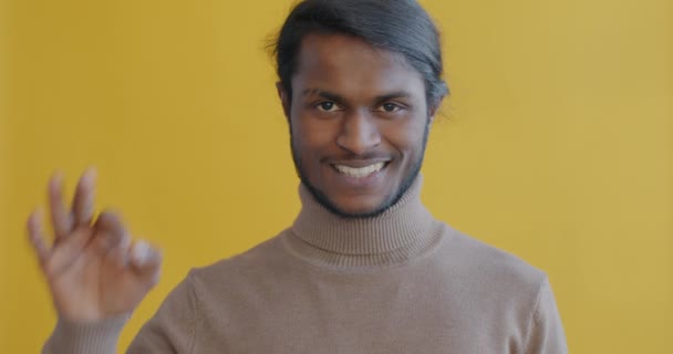明るいインド人男性のスローモーションポートレート笑顔と黄色の背景に満足を表現 をジェスチャー 肯定的な感情や人々の概念 — ストック動画