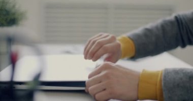 Genç iş adamının dizüstü bilgisayarı açtığı ve ofiste bilgisayarla yazı yazdığı yakın çekim. Modern teknoloji ve girişimci konsepti.