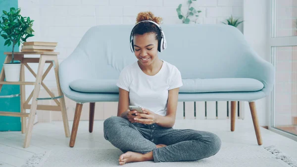 여자는 스마트폰 화면에 집에서 바닥에 헤드폰으로 음악을 들으며 됩니다 Millennials — 스톡 사진