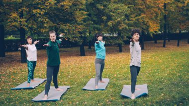 Genç kadın savaşçı poz Virabhadrasana ayakta sonra üçgen Trikonasana yerel Park açık sınıf sırasında pozisyon yoga yapıyoruz. Gençlik ve sağlık kavramı.