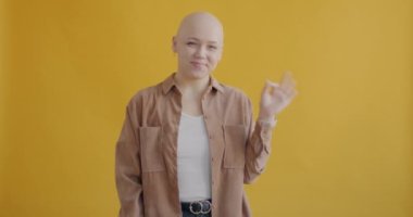 Tatmin olmuş genç bir kadının portresi el hareketi yapıyor ve sarı arkaplanda gülümsüyor. Duygular ve ifadeler kavramı.