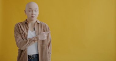 Boş alanı gösteren mutlu kız sarı arka plandaki kameraya bakarak gülümsemeyi tavsiye ediyor. Reklamcılık ve gençlik konsepti.