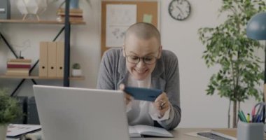 Mobil video oyunu oynayan mutlu bir kadının portresi iş arasında akıllı telefon ekranına dokunuyor. İnsanlar ve teknoloji kavramı.
