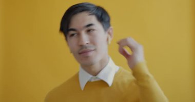 Neşeli öğrenci sarı arka planda modern kablosuz kulaklıkla müzik dinleyerek dans ediyor. Aygıtlar ve gençlik kültürü kavramı.