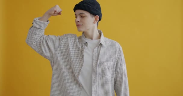 Zpomalený Portrét Veselého Teenagera Ukazujícího Biceps Usmívajícího Žlutém Pozadí Koncept — Stock video