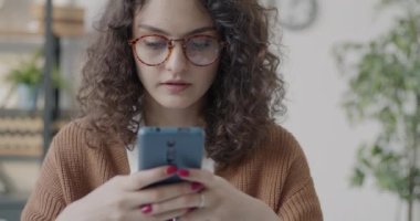 Akıllı telefon kullanan, mesaj atan, gülümseyen yalnız çalışan bir kadın. Modern teknoloji ve iletişim konsepti.