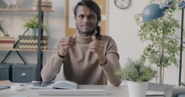 Hintli bir adamın portresi ofis telefonuyla konuşurken ve işaret ederken çevrimiçi video görüşmesi yapıyor. İş iletişimi ve teknoloji kavramı.