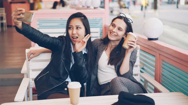 Беззаботные Девушки Делают Селфи Напитками Сидя Кафе Вместе Используя Смартфон — стоковое фото