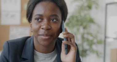 Ofiste tek başına çalışan, cep telefonuyla konuşan ve gülümseyen kadın girişimcilerin yakın çekimi. İletişim ve modern teknoloji kavramı.