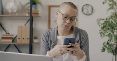 Akıllı telefon kullanan, sosyal medyayı kontrol eden ve işte gülümseyen neşeli iş kadınının portresi. Modern teknoloji ve gençlik kavramı.