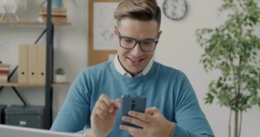 Neşeli bir çalışan bilgisayar oyunuyla rahatlıyor akıllı telefon ekranına dokunuyor ve modern eğlencenin tadını çıkarıyor. Teknoloji ve oyun konsepti.