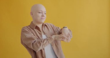 Yavaş çekimde dans eden neşeli öğrencinin sarı arka planda müzik dinlemekten zevk alışının portresi. Pozitiflik ve gençlik yaşam tarzı kavramı.