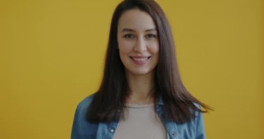 Sarı arka planda kameraya bakarak gülümseyen donutlarla eğlenen mutlu bir kadının portresi. Lezzetli yemekler ve olumlu duygu kavramı..