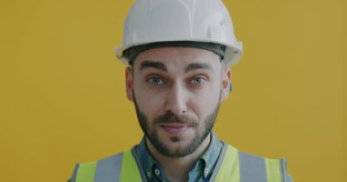 Üniformalı, şapkalı, sarı arka planda gülümseyen neşeli işçilerin yakın plan portresi. Meslek ve kariyer kavramı.