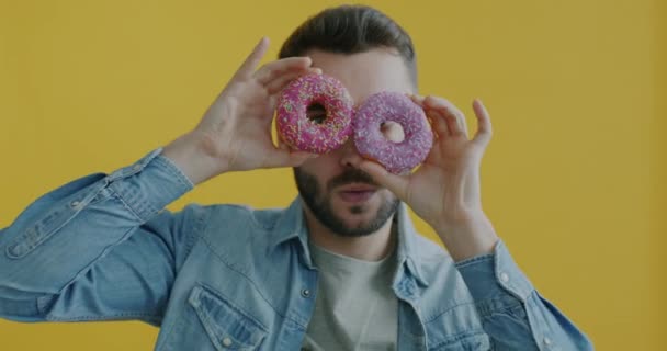Медленный Портрет Веселого Молодого Человека Держащего Пончики Веселящегося Делая Конфетные — стоковое видео