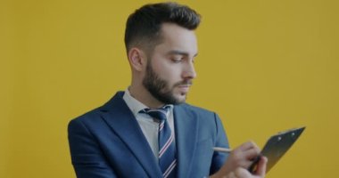 Girişimci portresi, sadece sarı arka planda duran ve çalışan iş fikirlerini kağıda döküyor. İş adamları ve evrak işleri kavramı.