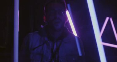 Neon ışıklarda tek başına dans eden neşeli bir adamın ağır çekimde çekilmiş portresi uzayı aydınlattı. Çok renkli arka planda hareket eden kolları rahatlatan yakışıklı bir adam..