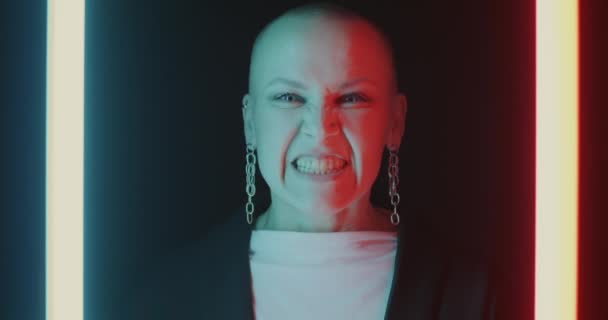 ネオンの光で黒の背景に歯を示す積極的な若い女性のクローズアップ肖像画 否定的な感情と人間の表現の概念 — ストック動画