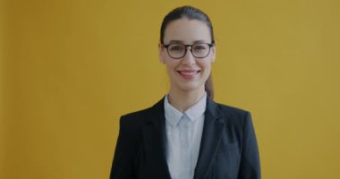 Resmi giyinmiş mutlu bir iş kadını portresi el hareketini gösteriyor ve sarı arka planda gülümsüyor. Başarı ve iş adamı konsepti.