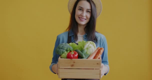 Sarı Arka Planda Taze Sebzeli Ahşap Kutu Taşıyan Üniformalı Kadın — Stok video