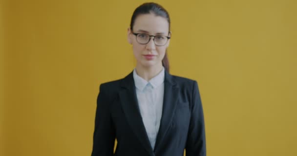 黄色の色の背景に立ってカメラを指して正式な服で魅力的な若い女性の肖像画 ビジネスと起業家のコンセプト — ストック動画