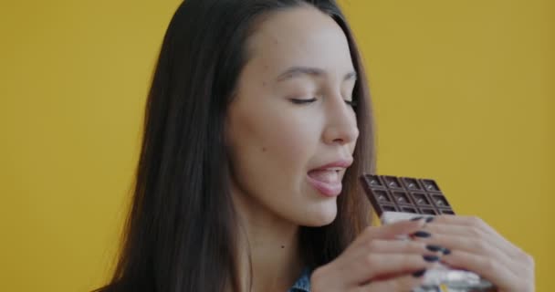 Close Retrato Bela Jovem Comendo Chocolate Mastigando Sorrindo Fundo Amarelo — Vídeo de Stock
