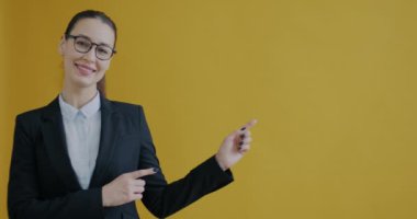 Takım elbiseli kadının portresi, sarı arka planda gülümseyen boş uzay kenarlarına bakıyor. İş adamları ve reklam kavramı.