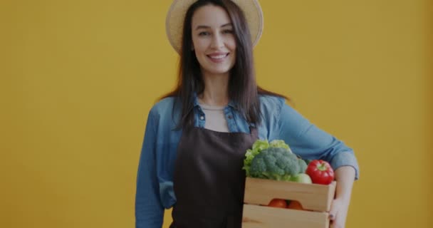 女性农民持有新鲜蔬菜并在黄色背景上签署有机标志的肖像 健康营养和食品杂货概念 — 图库视频影像