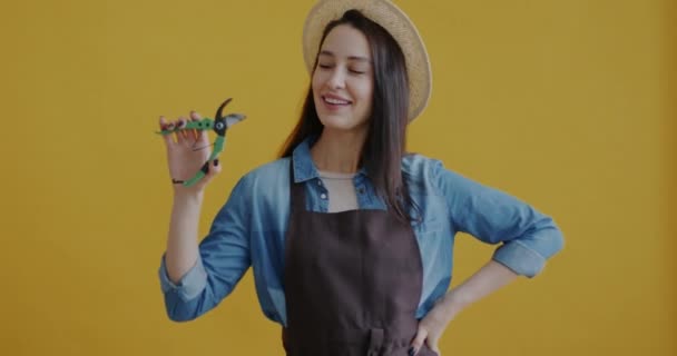 年轻的女园丁拿着剪子站在黄色背景上笑的形象 园艺工具和积极情绪概念 — 图库视频影像