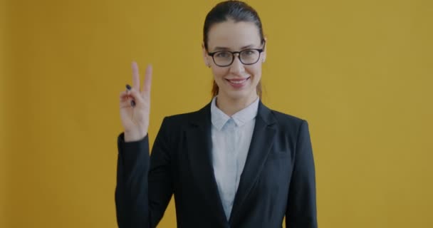 Портрет Молодой Предпринимательницы Поднимающей Руку Жестом Знака Улыбающейся Желтом Фоне — стоковое видео