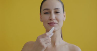 Sarı arka planda cilt bakımının keyfini çıkaran Guasha kazıyıcısı ile masaj yapan güzel bir kadının yakın plan portresi. İnsanlar ve güzellik konsepti.