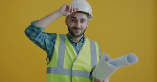 청사진을 기술자의 움직임은 헬멧을 만지고 노란색 배경에 미소를 노동자 — 비디오