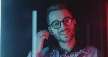 Neşeli öğrencilerin yakın plan portresi kablosuz kulaklıklar takıyor ve parlak neon ışıklı arka planda dans ediyor. Modern teknoloji ve gençlik kültürü kavramı.