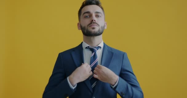 重要な仕事の準備を取得し 黄色の背景にカメラを見てネクタイを固定エレガントな若い男の肖像画 人とビジネスの概念 — ストック動画