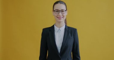 Sarı arka plandaki kameraya gülümseyen güzel iş kadını portresi. İş adamları ve olumlu duygu kavramı.