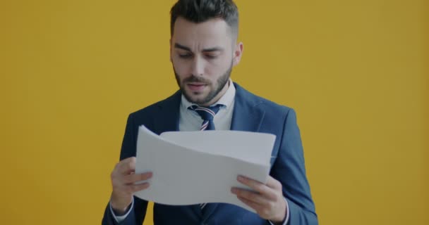 一个疲惫的商人在黄色背景下阅读文件 然后抛出文件和微笑的画像 业务和文书工作概念 — 图库视频影像