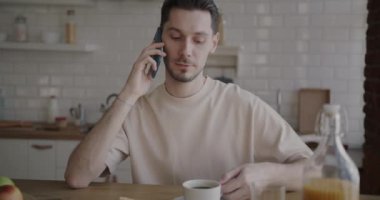 Neşeli öğrenci portresi cep telefonuyla konuşuyor ve mutfakta kahve içiyor. İletişim ve gençlik yaşam tarzı kavramı.