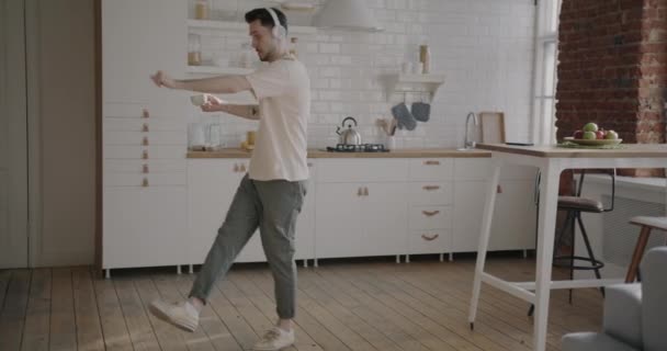 Unbekümmerter Junger Mann Tanzt Mit Tasse Kaffee Und Hört Musik — Stockvideo