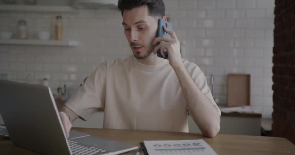 프리랜서가 노트북으로 일하고 부엌에서 전화로 얘기하는 — 비디오