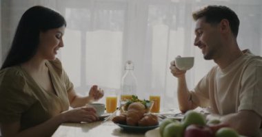 Kadın ve erkek sabah kahvaltının tadını çıkarıyorlar ve rahat bir mutfakta sohbet ediyorlar. İlişki ve ev hayatı kavramı.