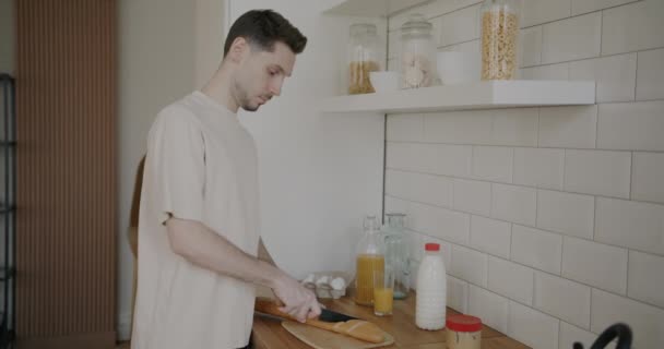 年轻人慢吞吞地在现代厨房切新鲜的面包 微笑着 食物制作和家庭生活方式概念 — 图库视频影像