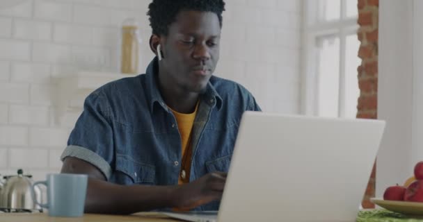 아프리카 미국인 프리랜서는 노트북으로 일하고 부엌에 이어폰으로 음악을 듣는다 사람들 — 비디오