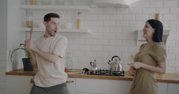 有趣的男人和女人在家里玩击剑游戏 在厨房里笑着享受闲暇的无忧无虑的活动 青年生活方式和乐趣概念 — 图库视频影像